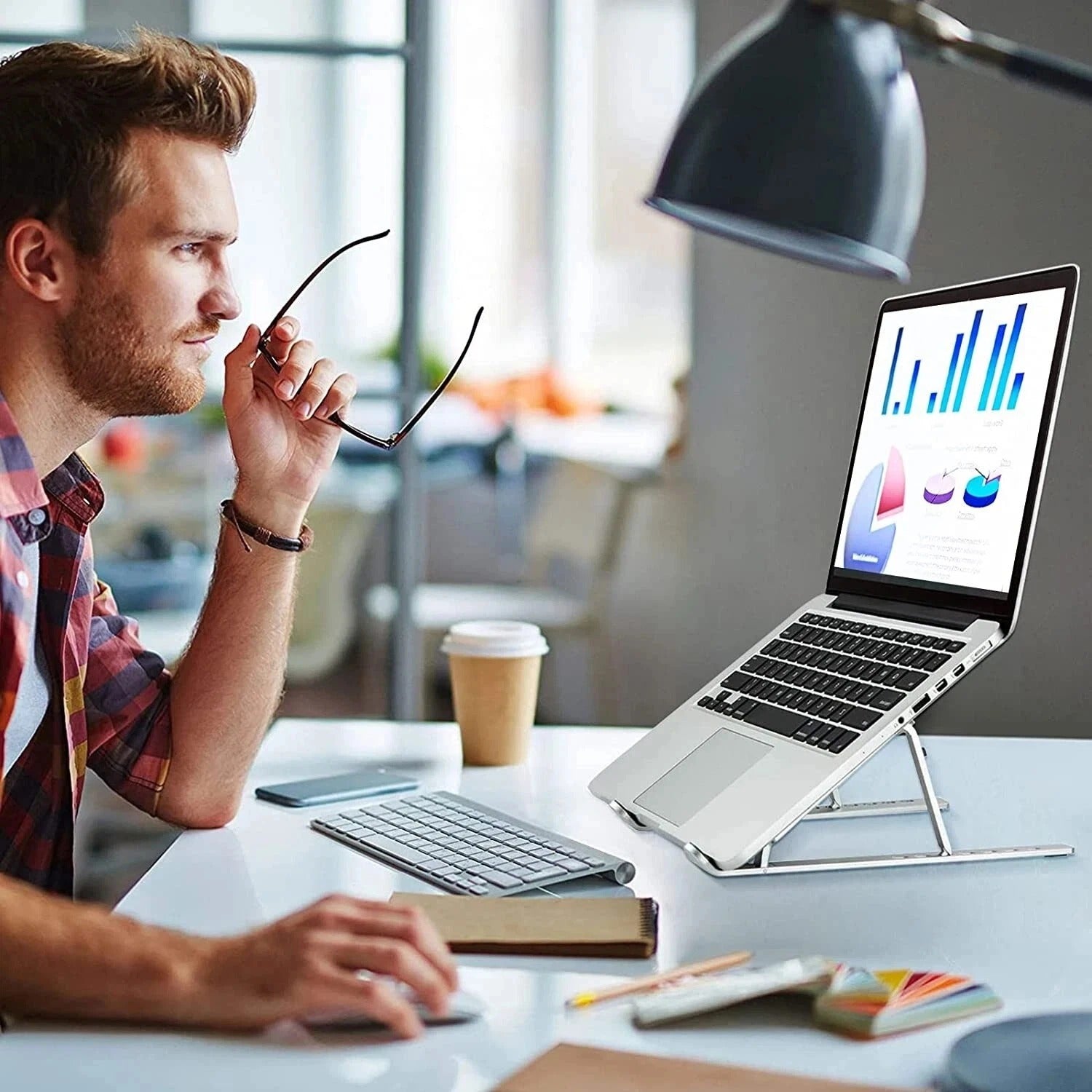 Silver laptop stand holding an open laptop on a desk at an angle